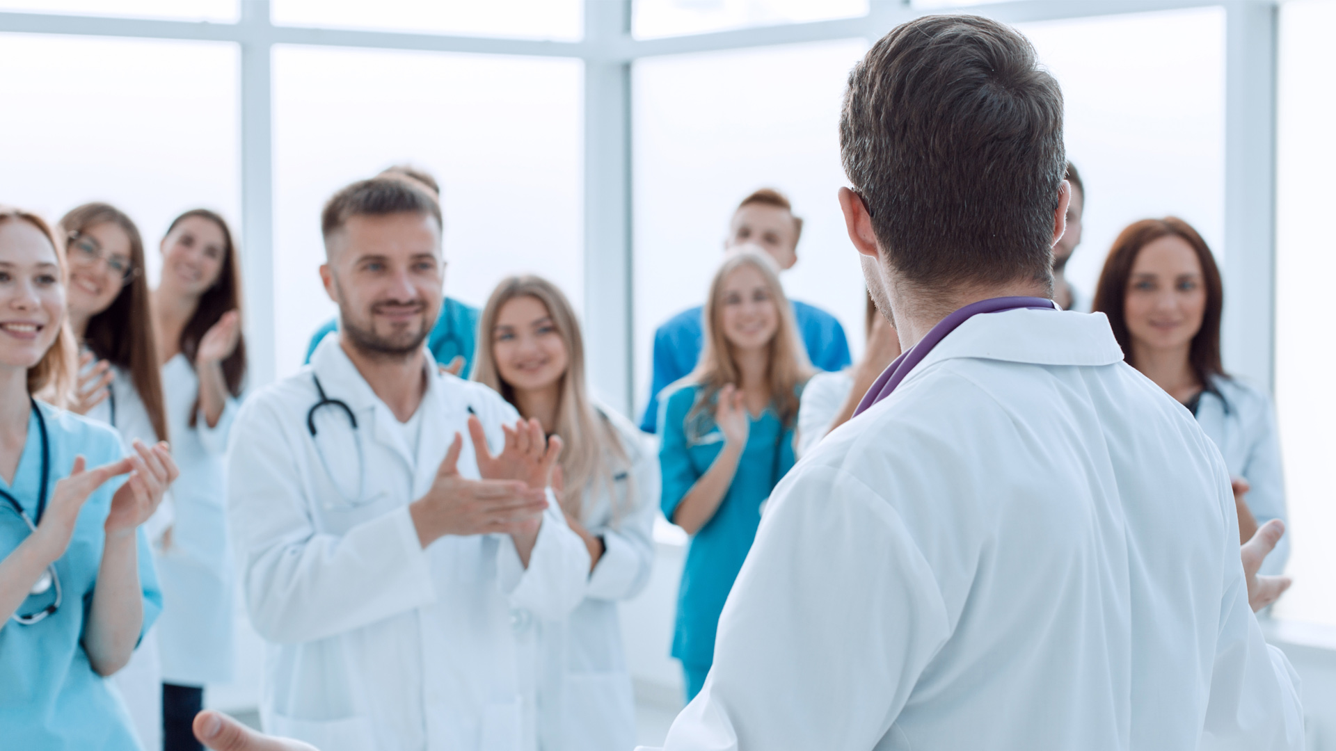 Ärztinnen und Ärzte applaudieren, während ein Kollege einen Vortrag hält