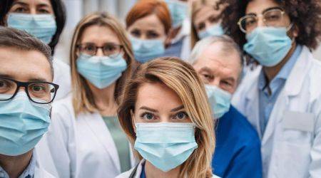 Mehrere Aerztinnen und Aerzte mit Atemmasken schützen sich vor Corona im Krankenhaus