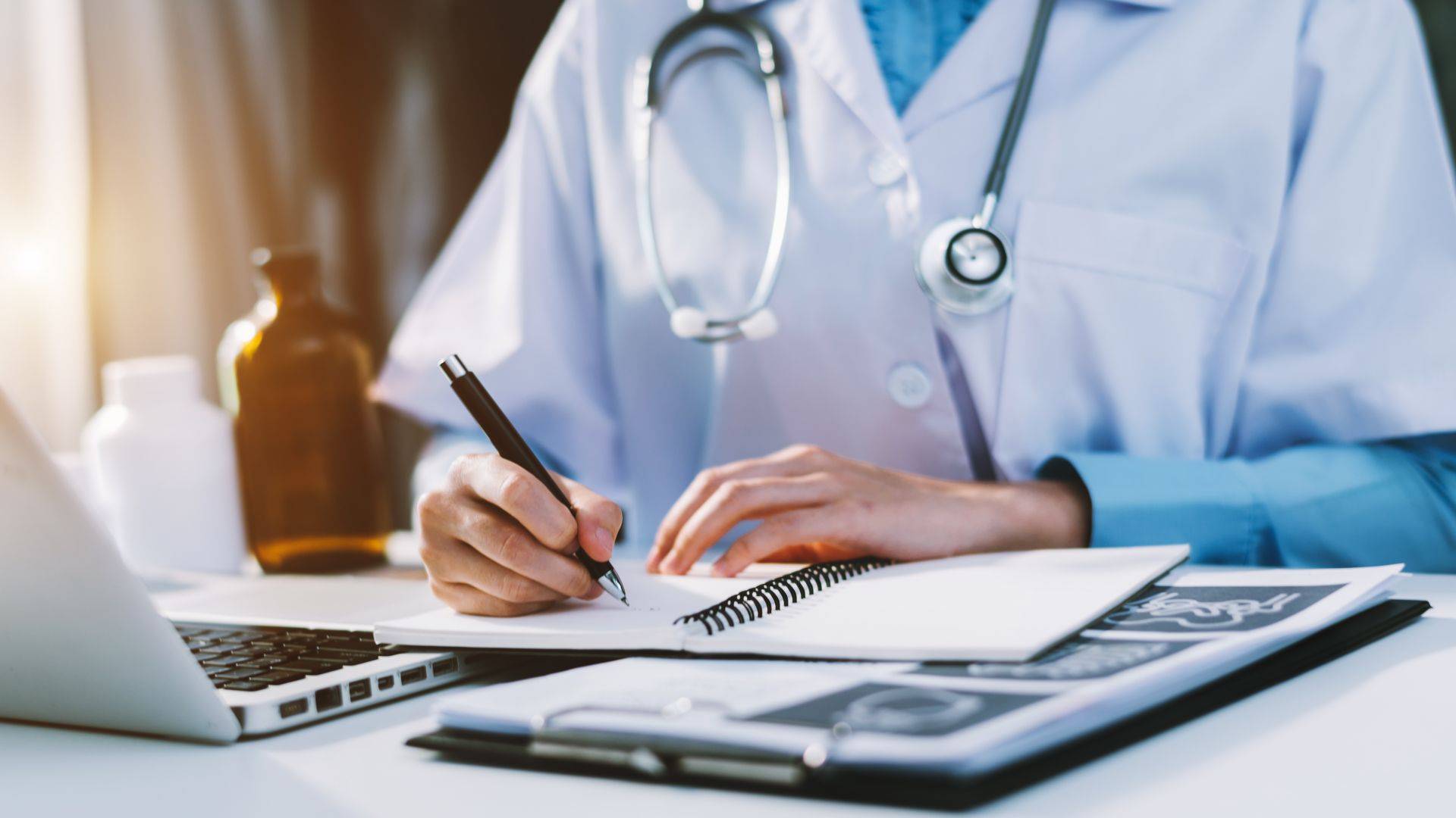 Ein Nachwuchsarzt sitzt am Schreibtisch und macht sich Notizen