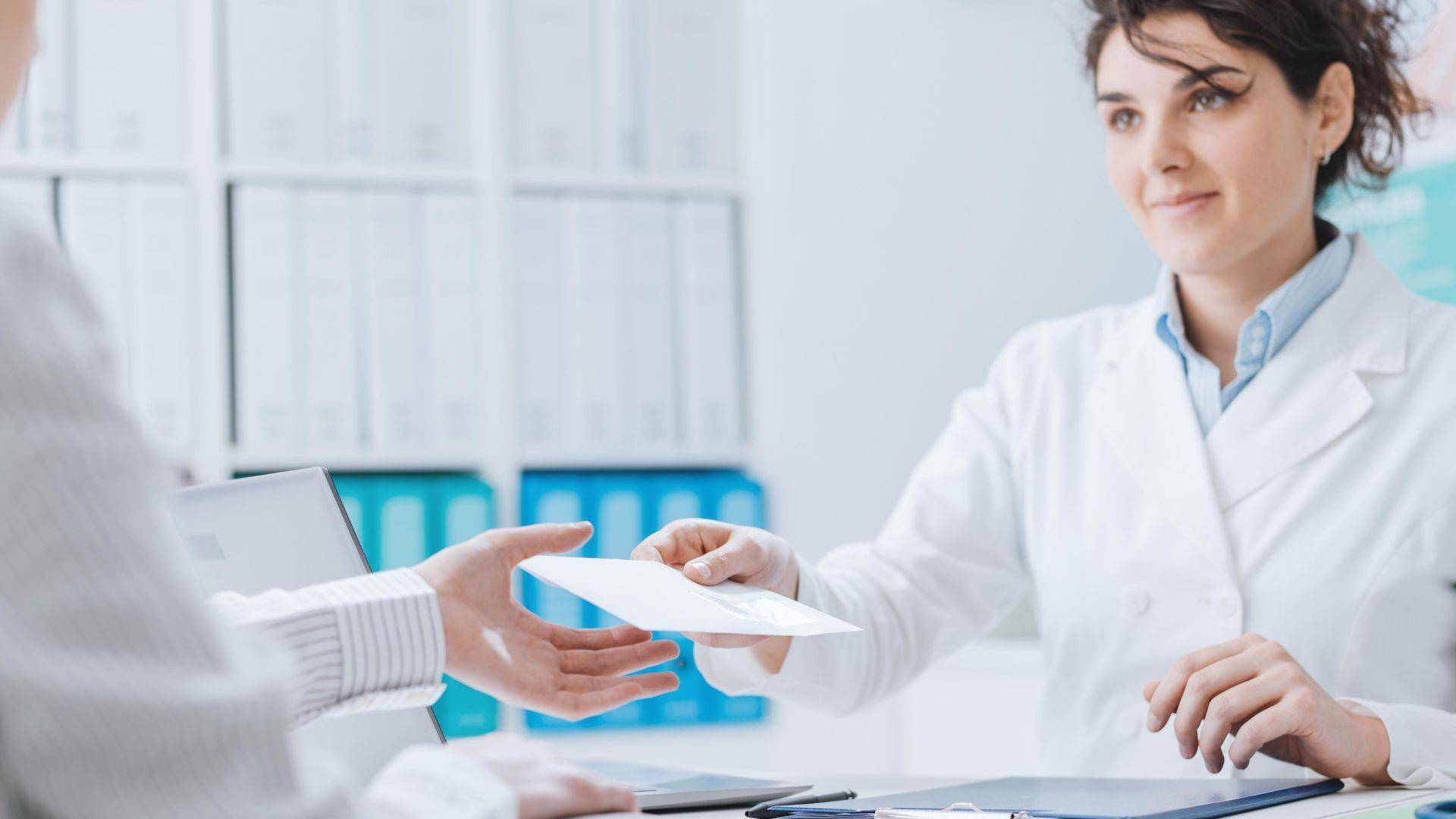 Ärztin überreicht Patient einen Arztbrief