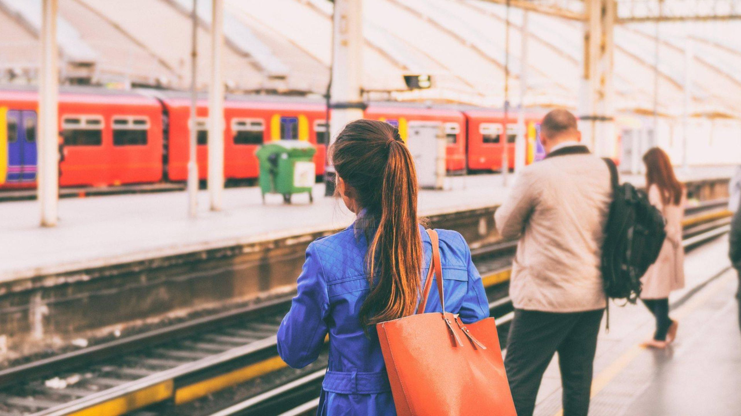 Personen stehen am Bahnsteig um in die Arbeit zu pendeln