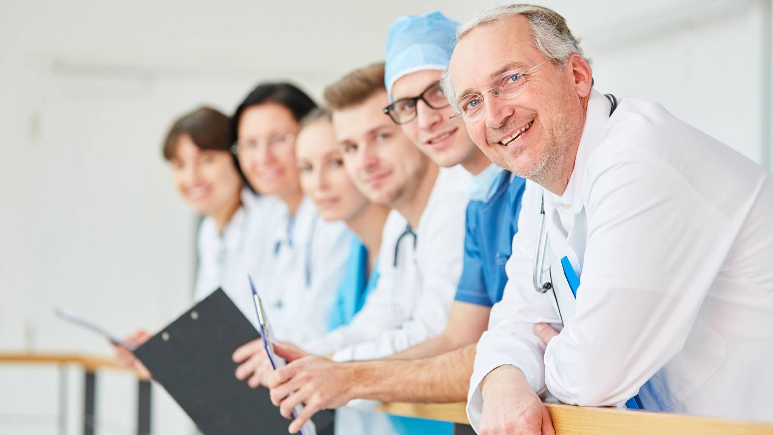 Mehrere Ärztinnen und Ärzte stehen über ein Geländer gelehnt
