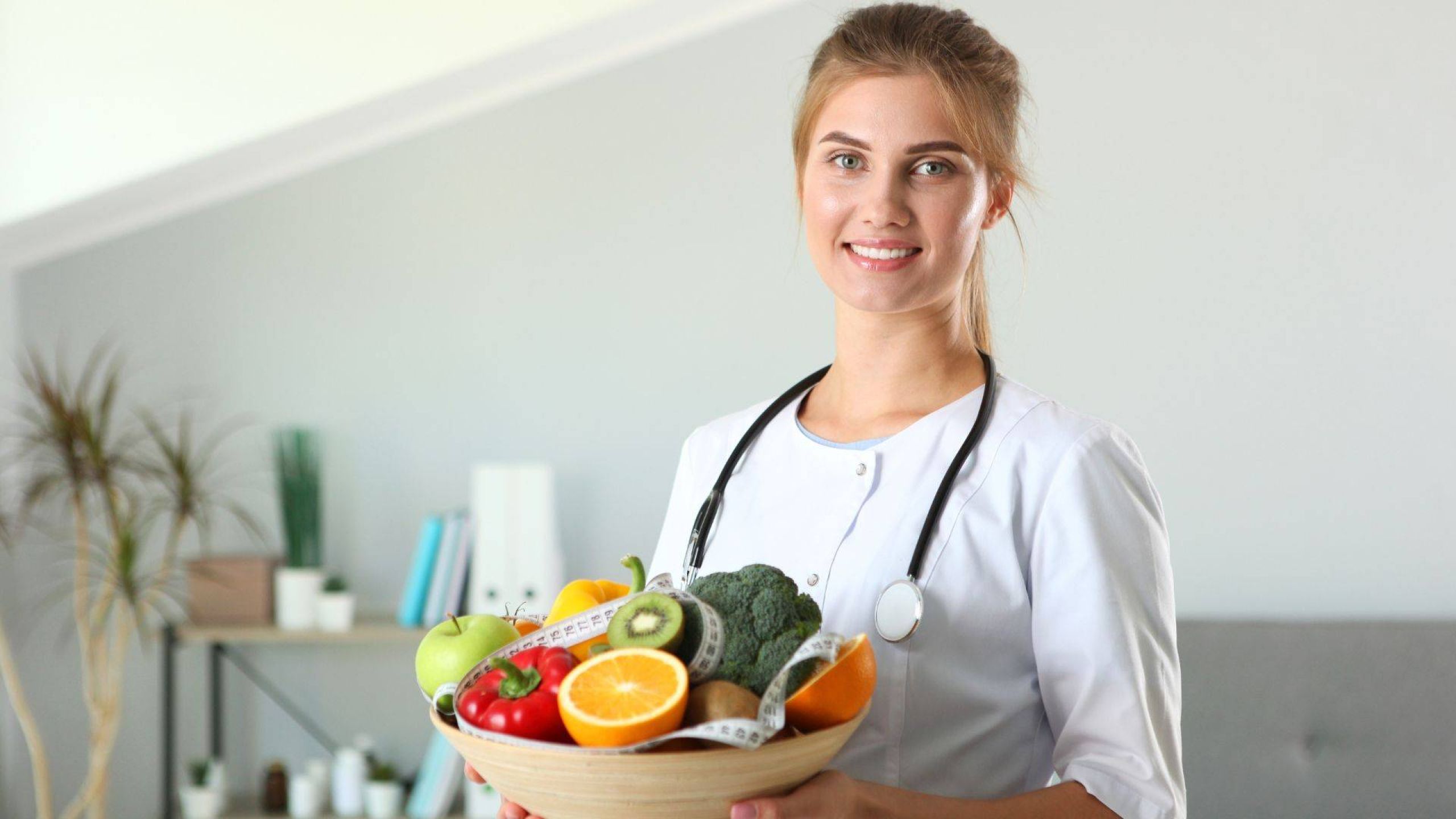 Junge Ärztin mit Obst und Gemüse in der Hand