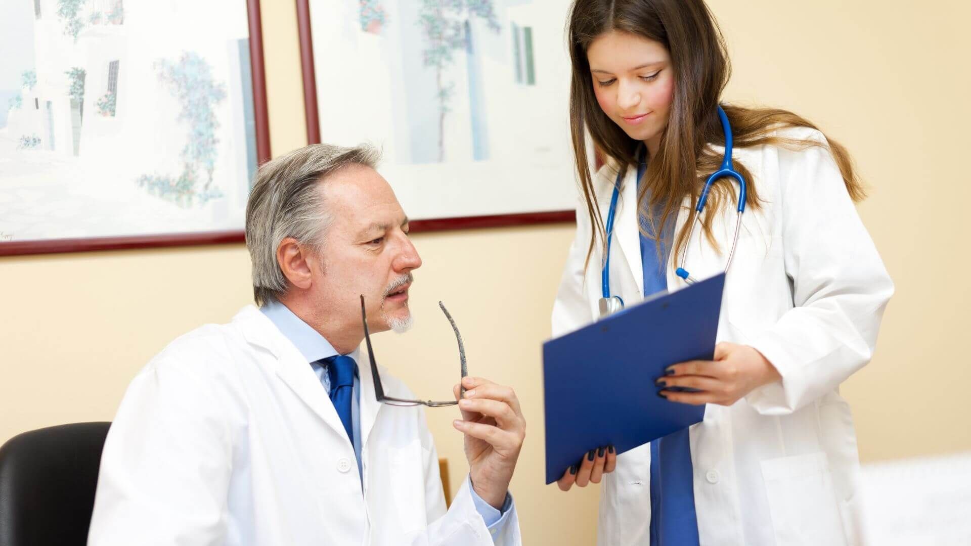 Junge Ärztin zeigt Arzt eine Patientenmappe 