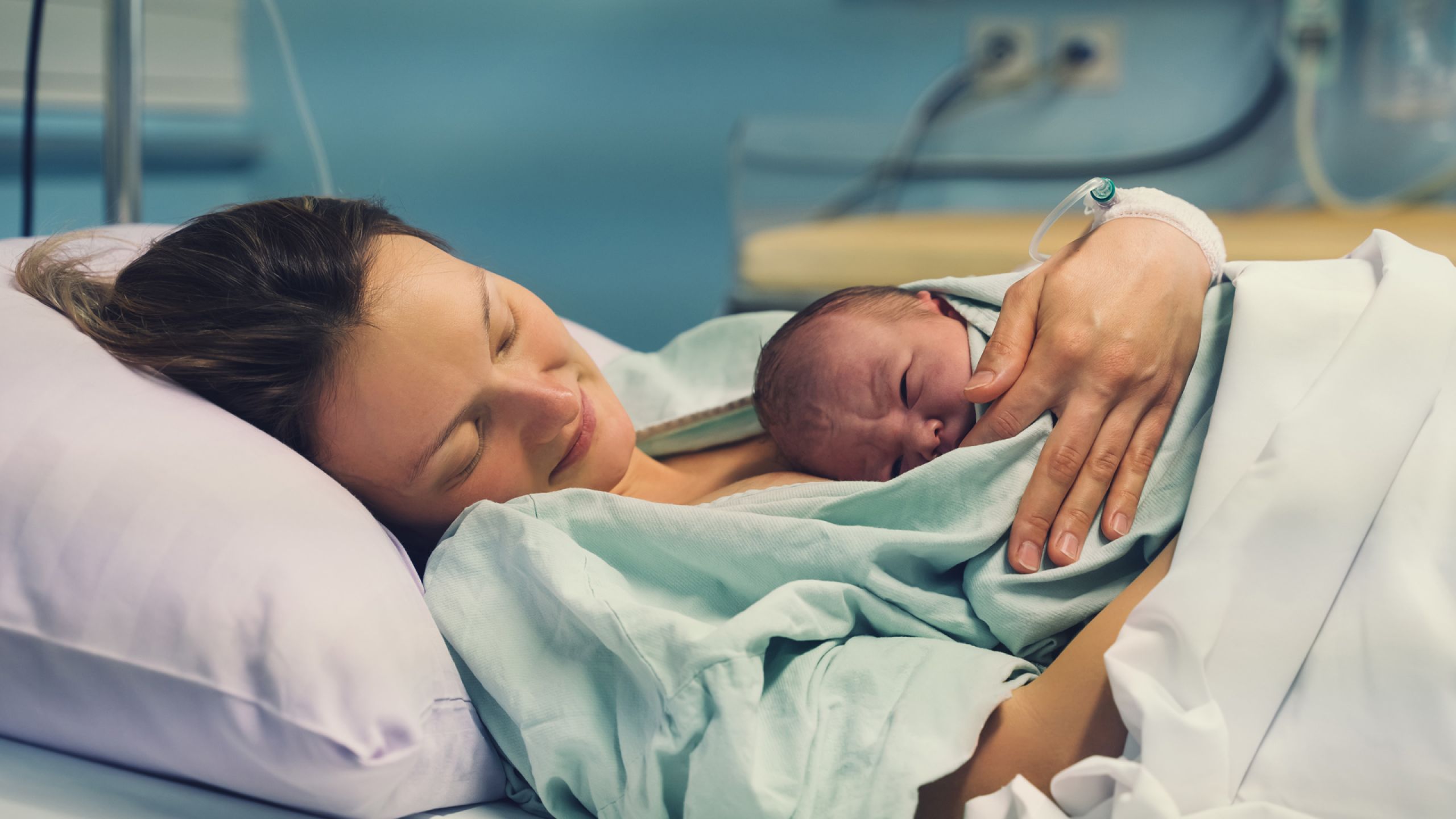 Junge Frau hält ein Neugeborenes im Arm
