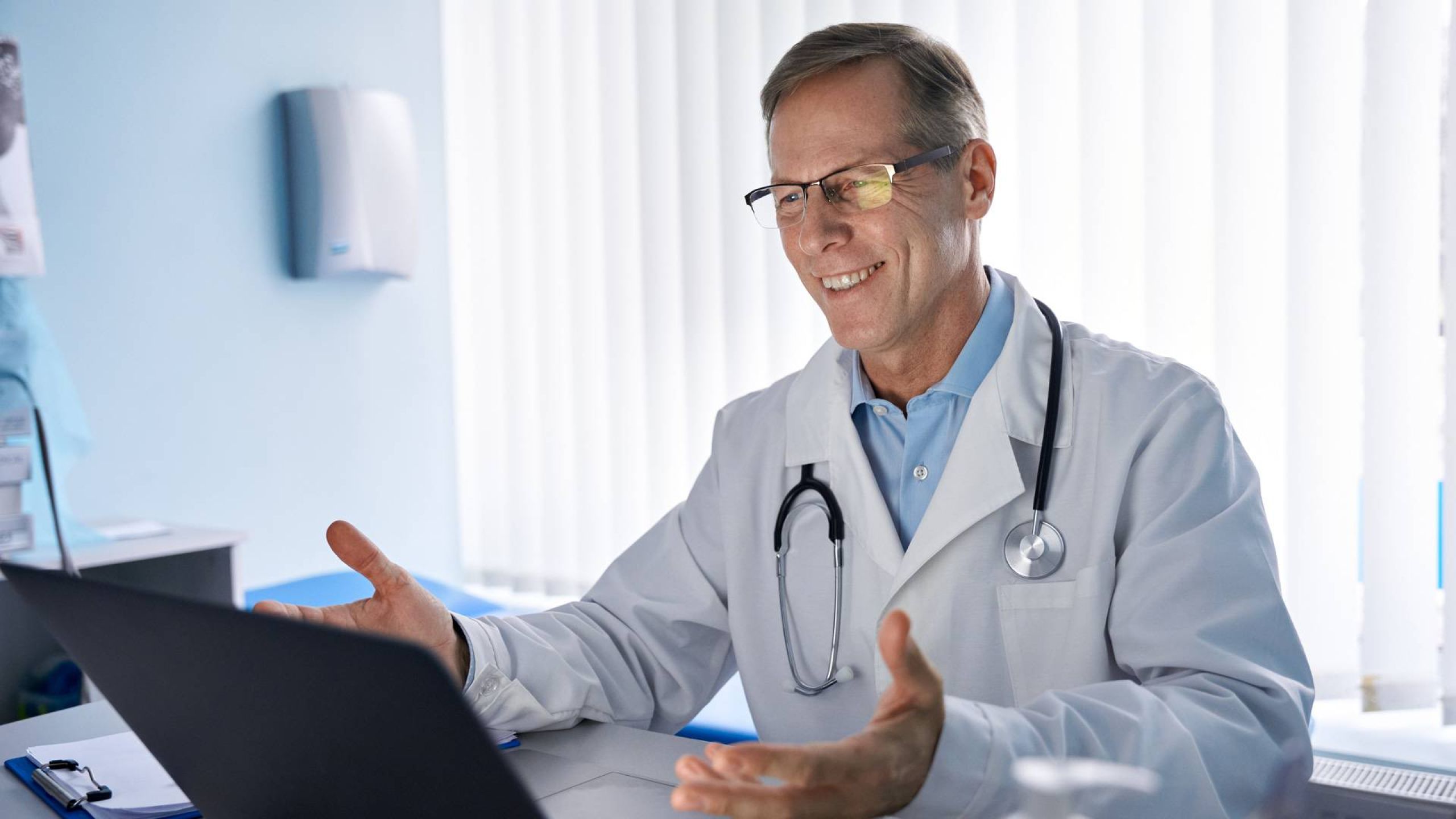 Arzt sitzt dank funktionierender Praxissoftware lächelnd vor einem Computerbildschirm