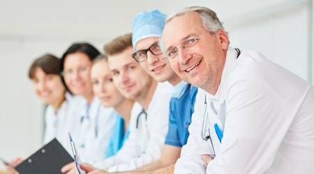 Mehrere Ärzte und Ärztinnen verschiedenen Alters lehnen sich über ein Geländer