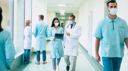Ärztin und Arzt laufen zusammen über einen Gang im Krankenhaus