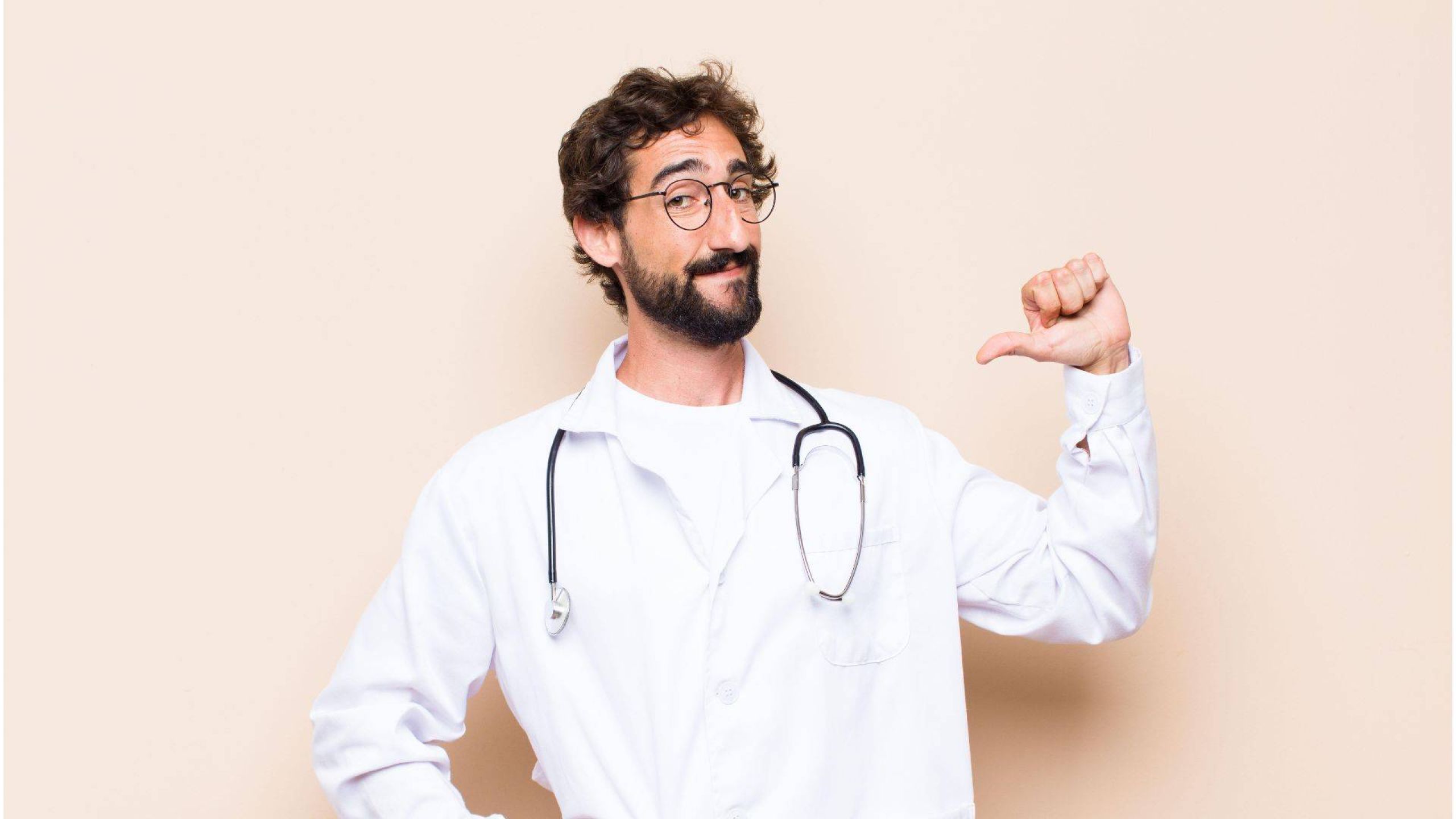 Arzt blickt stolz in die Kamera und zeigt dabei auf sich selbst