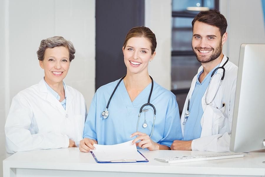 Drei Ärzte stehen lächelnd im Aufnahmebereich einer medizinischen Einrichtung