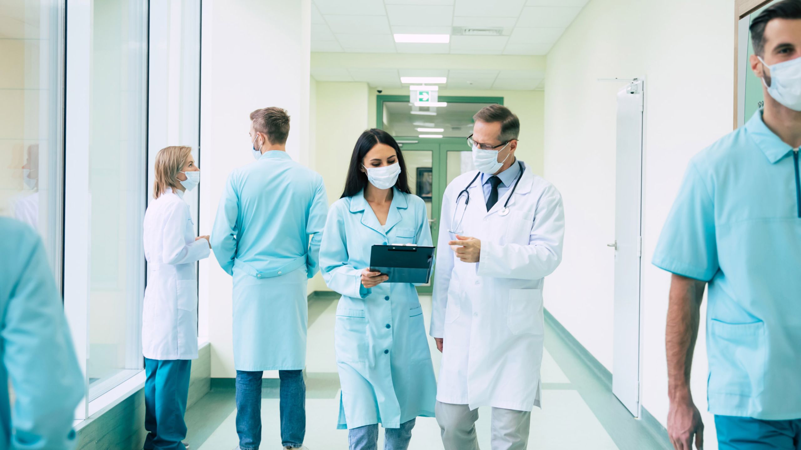 Ärztin und Arzt laufen über einen Gang im Krankenhaus