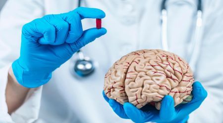 Ein Arzt hält eine Tablette und ein menschliches Gehirn in Händen