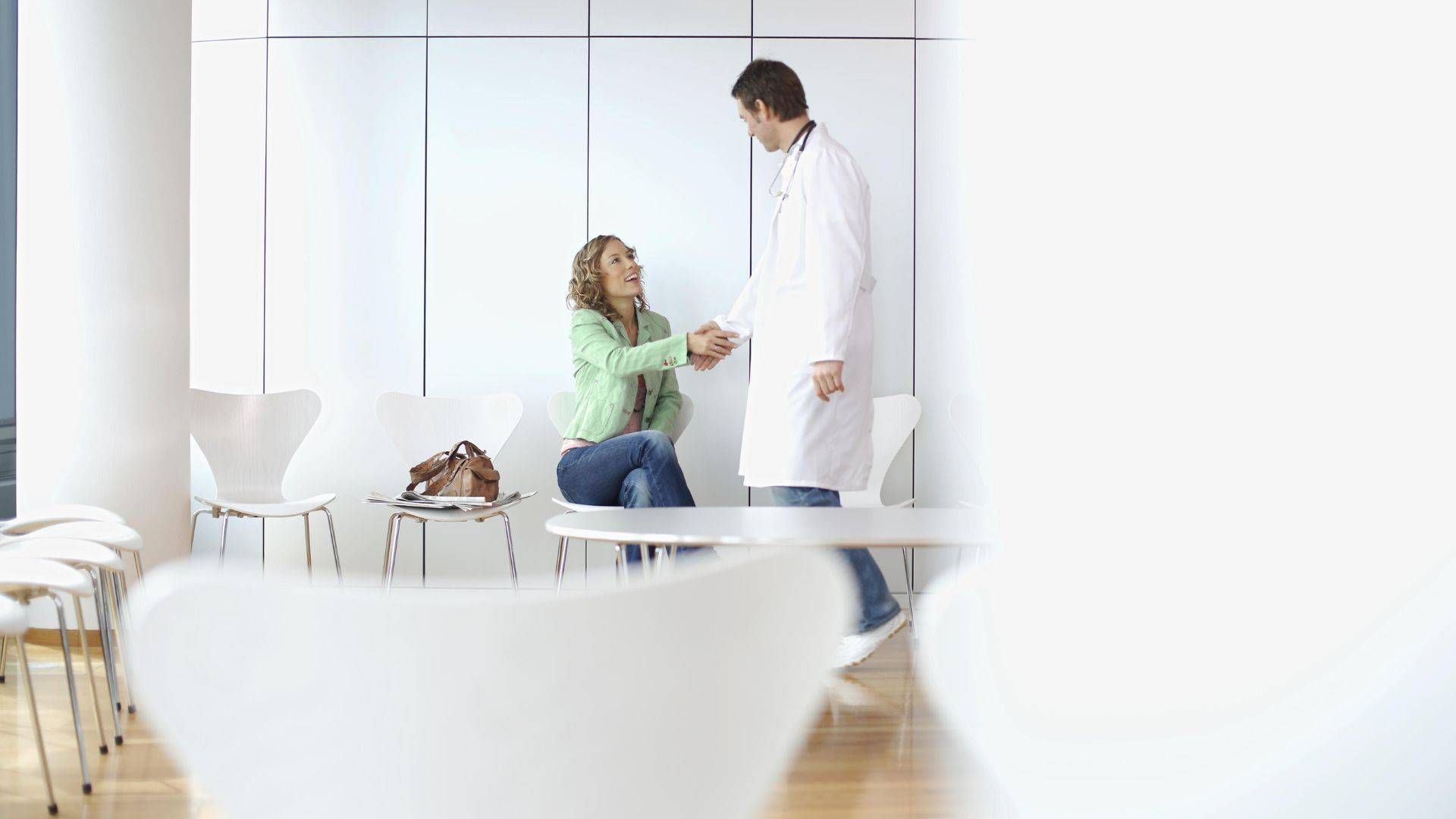 Arzt gibt Patientin in seiner finanzierten Praxis die Hand