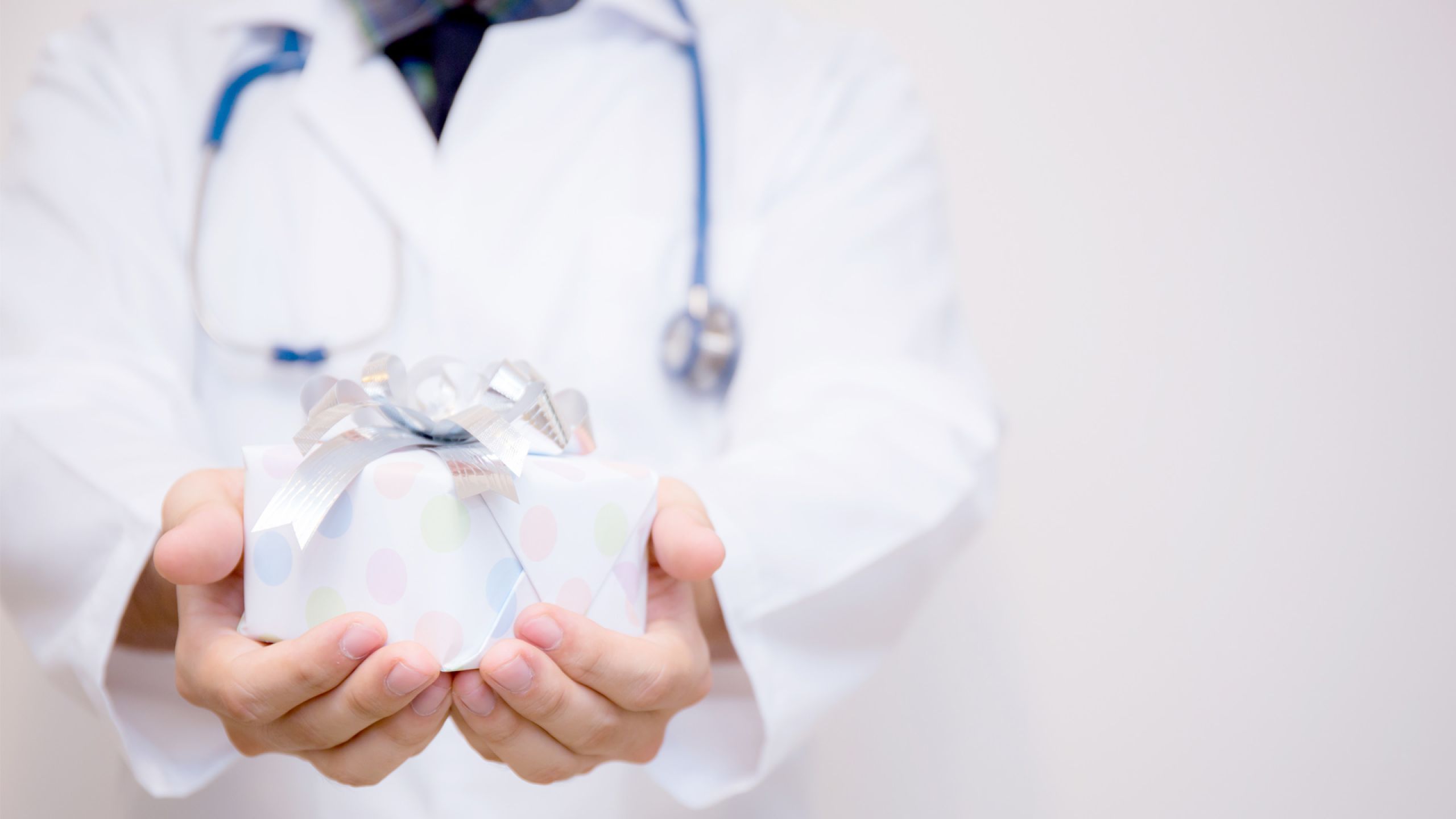 Mediziner hält ein Geschenk in den Händen und streckt es nach vorne