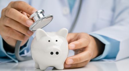 Ein Arzt überprüft mit einem Stethoskop metaphorisch die Ersparnis aus seinem Facharzt Gehalt